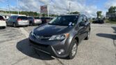 Close-up of a gray Toyota SUV in a car dealership lot with other vehicles and an EZ Loan Auto Sales sign in the background.