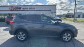 Front view of a gray SUV in a car dealership lot with the E-Z LOAN AUTO SALES storefront and a blue sky above.
