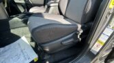 Left-hand-drive car interior with front seats and center console; papers lying on the driver's side floor mat near the gear shifter and door with warning labels visible on the frame.