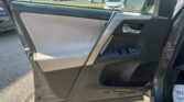 Front passenger door interior with gray fabric panel, silver handle, and window controls; dealership lot visible through window.
