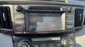 Car stereo and climate control panel in a vehicle center console with a touchscreen display and various buttons and dials to adjust audio and climate.