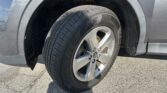 Close-up of a car tire mounted on an alloy wheel inside the wheel well of a gray SUV edge, showing tread and rim.