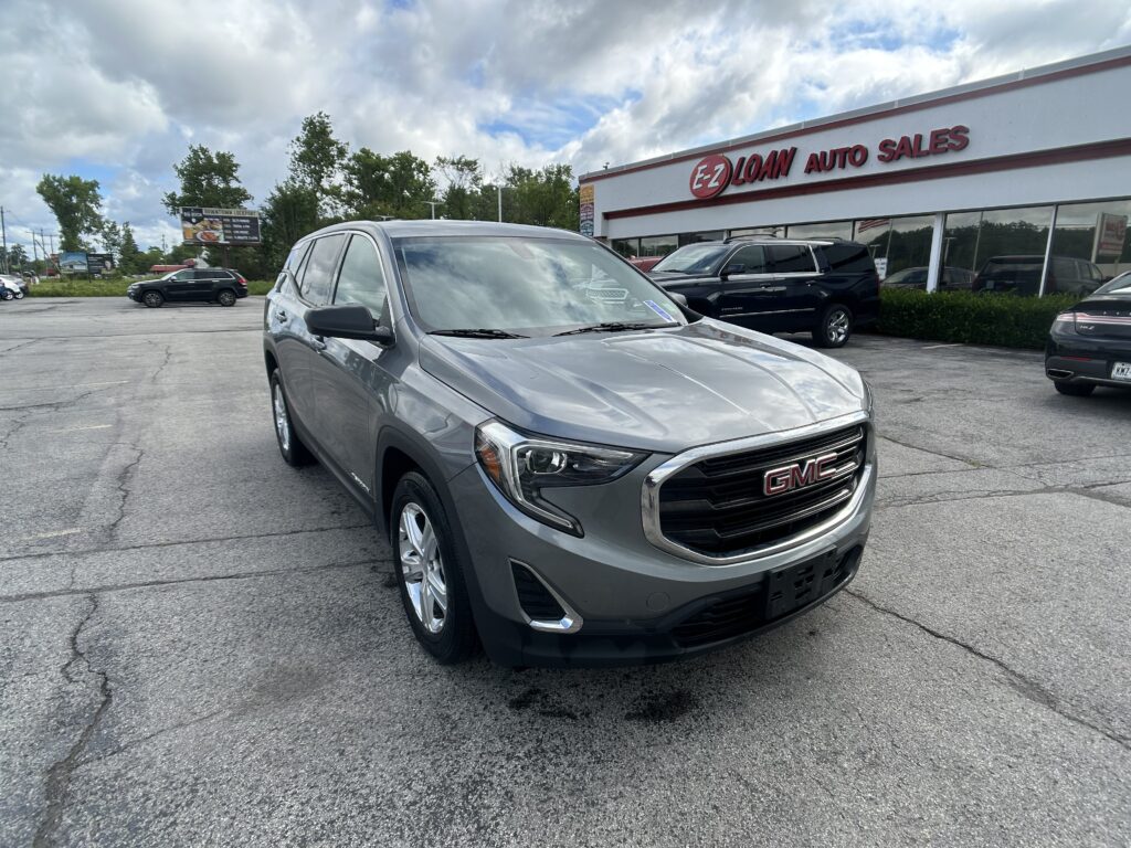 Silver GMC SUV in the foreground at an auto dealership, with an E-Z Loan Auto Sales building in the background on a cloudy day.