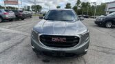 Front view of a gray GMC SUV in a car dealership lot, with other vehicles and an EZ Loan Auto Sales sign in the background.