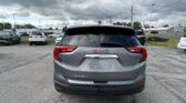 Rear view of a GMC Terrain SUV in a parking lot with other cars and a cloudy sky.