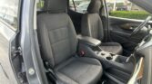 Front interior of a car with two black fabric seats, center console, and steering wheel; driver’s door is open to the outside.