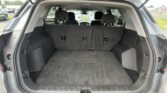 Rear cargo area of a SUV with dark carpeting and three upright rear seats visible, viewed from the open tailgate.
