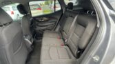 Back seat of a car with black fabric seats, orange stitching, headrests, and visible seat belts; outside cars seen through the windows.