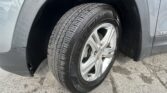 Close-up of a tire on a silver GMC alloy wheel inside a gray car fender, with road surface visible below.