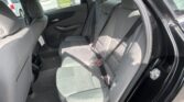 Rear car seat interior with gray fabric upholstery, visible seat belts and door panel, view of parked cars outside through the window.