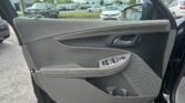 Car door interior with window controls, view of a parking lot outside through the open windowy side door panel in gray leather.