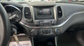 View from front passenger seat of a car interior, center touchscreen display, gear shifter, and dashboard with outside parking lot visible through windshield.