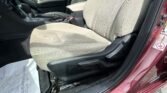 Beige cloth front seats and center console of a car, with gear shifter and seat belt buckle visible, photographed from the open driver’s side door.
