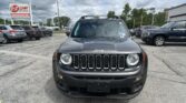 Front view of a dark gray Jeep SUV in a dealership parking lot with an EZ LOAN sign in the background.