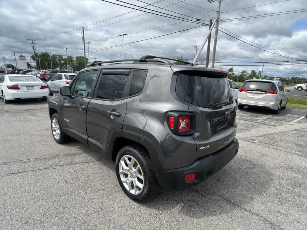 Rear three-quarter view of a dark gray Jeep Renegade 4x4 in a parking lot with other cars and utility poles overhead.