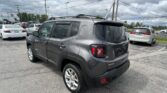 Rear three-quarter view of a dark gray Jeep Renegade 4x4 in a parking lot with other cars and utility poles overhead.