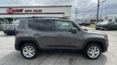 Grey Jeep Renegade SUV in foreground at a used-car lot with E-Z Loan Auto Sales building in background.