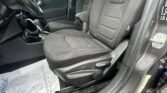Interior of a car with black fabric seats, steering wheel, and center console visible from the driver’s side door open.