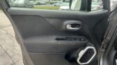 Interior of a car door panel with window and side mirror visible, showing a parking lot through the glass.