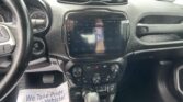 Car interior dashboard with a center touchscreen displaying vehicle controls, gear shifter in foreground, and steering wheel on left