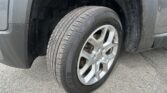 Front wheel of a dark van with a dusty tire and alloy rim, visible brake rotor behind the spokes, and wheel well above.