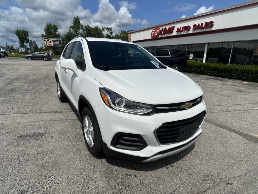 White Chevrolet SUV parked in a dealership lot with the EZ Loan Auto Sales building in the background.