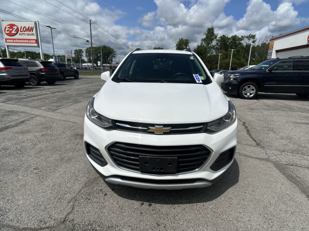 Front view of a white Chevrolet SUV in a car dealership lot, with the E-Z LOAN Auto Sales sign visible in the background.