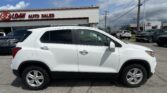 White SUV parked in front of an auto dealership with an EZ LOAN Auto Sales sign on the building and a Toyota dealership in the background.