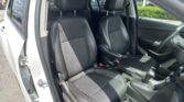 Front and rear black leather car seats with white stitching in a white SUV, driver’s door open at the side.