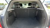 Open SUV trunk view showing black cargo area with rear seats upright and side panels; parking lot in background