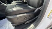 Interior of a car showing black leather front seats with brown stitching, center console, and seat adjustment controls on the side near the door.