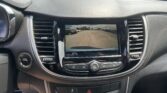 Car dashboard with a rearview camera display showing a parking lot and orange guiding lines behind the vehicle.