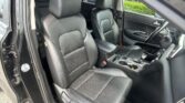 Front interior of a black car with black leather seats, center console, and a right-side steering wheel visible outside the door.