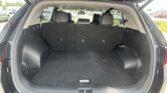 Open rear hatch of a black SUV showing a roomy cargo area with the rear seats upright and headrests visible in the background, parked in a lot.