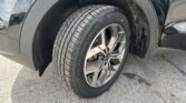 Close-up of a car wheel and tire, showing wet mud splashes on the tire and fender with a chrome rim partially visible.