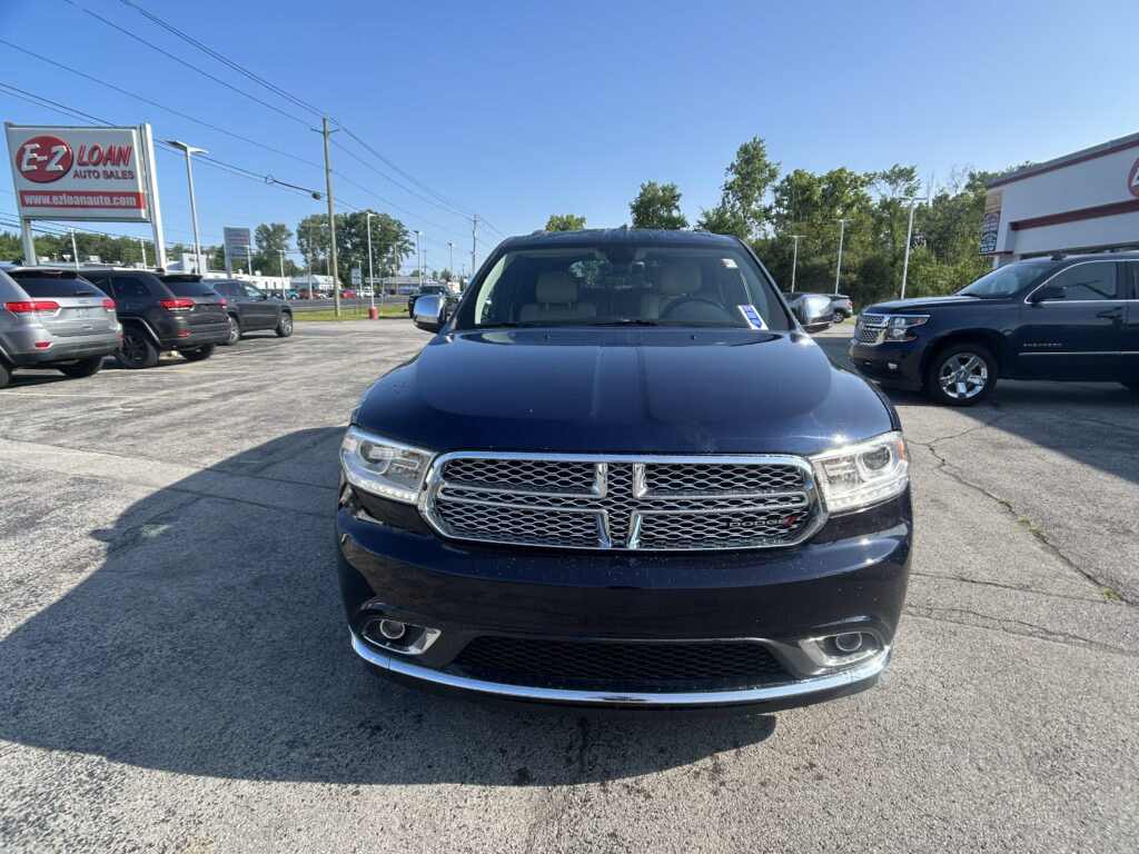 Front view of a black Dodge SUV in a car dealership lot with other vehicles and an EZ LOAN Auto Sales sign in the background.