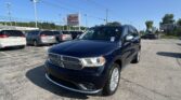Blue Dodge SUV in a dealership parking lot with other minivans and an EZ Auto Sales sign in the background on a sunny day