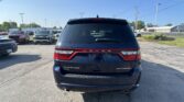 Rear view of a black Dodge Durango SUV in a parking lot with other cars and a clear blue sky above.