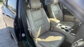Front passenger and driver seats in a beige leather SUV interior, open door, center console visible.