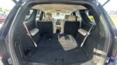 Open SUV cargo area with third-row seats folded, exposing dark carpet and beige interior panels