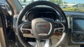 Car interior of a Dodge with steering wheel centered, dashboard visible, and dealership lot seen through the windshield.