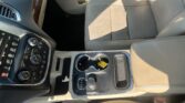Center console with gear shifter, cup holders, and beige perforated leather seats in a car interior.