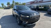Dark gray Jeep SUV in the dealership lot with EZ Loan Auto Sales storefront in the background on a sunny day.