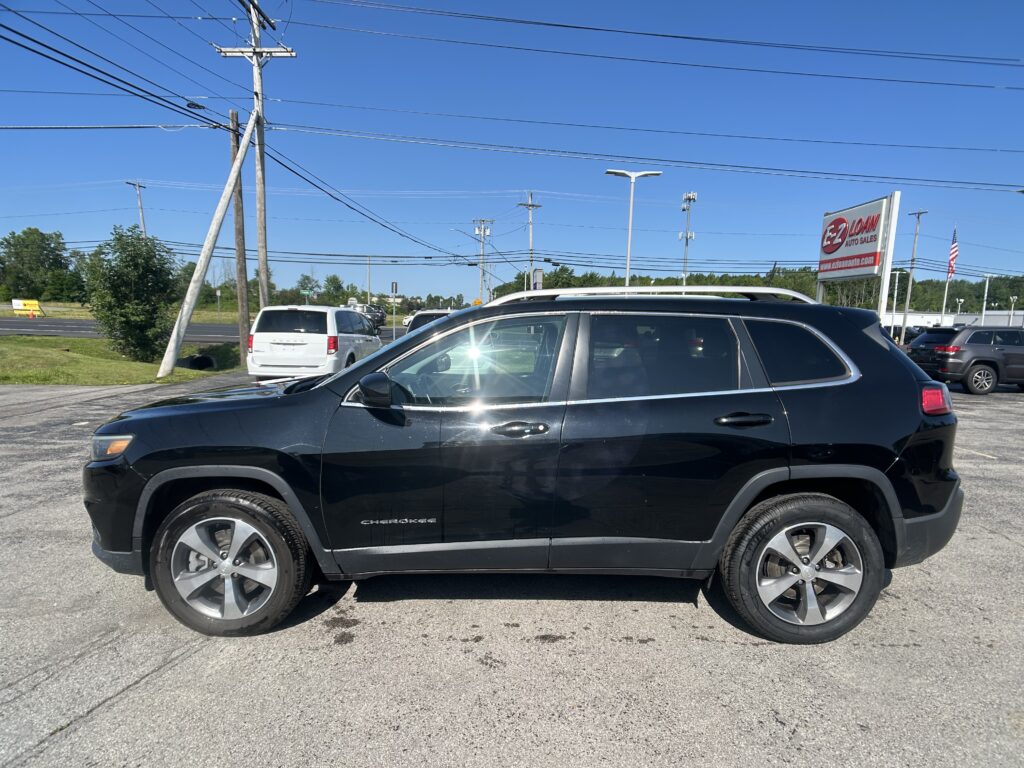 Black Jeep Cherokee in the foreground at a car lot, with power lines and an EZ Loan Auto Sales sign in the background.