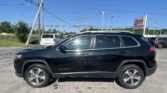 Black Jeep Cherokee in the foreground at a car lot, with power lines and an EZ Loan Auto Sales sign in the background.