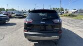 Rear view of a black Jeep Grand Cherokee Limited 4x4 in a busy parking lot with other cars and power lines in the background.