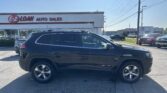 Black Jeep Cherokee parked in the lot in front of E-Z Loan Auto Sales storefront under a clear blue sky.
