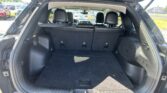 Open hatchback showing empty cargo area with rear seats upright in a dark SUV; parking lot with cars in background.