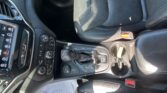 Interior of a car showing the center console with gear shifter, climate controls, and a perforated leather seat to the right.