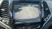 Rearview camera display showing a parking lot with green, yellow, and red guiding lines and the message 'Check entire surroundings'.